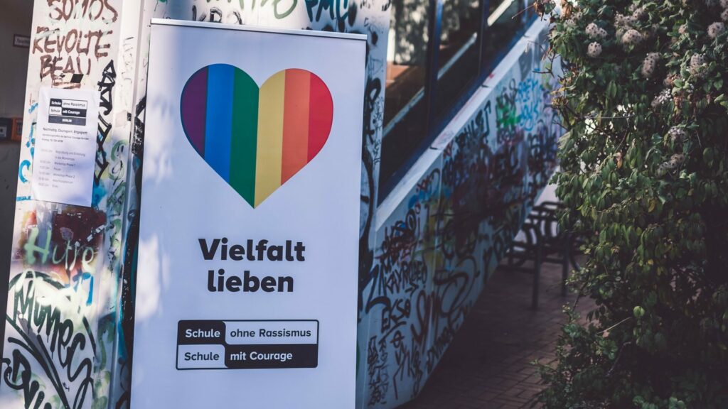 Ein Plakat mit der Aufschrift Vielfalt Lieben hängt vor einem Schulhaus
